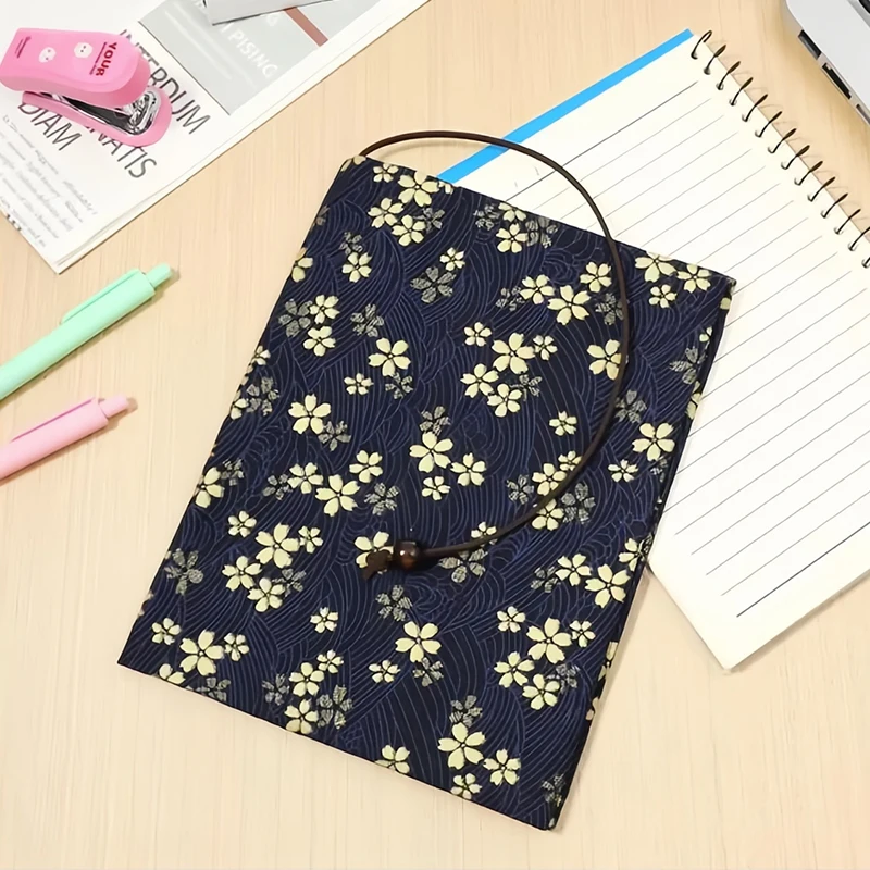 Couvre-livre à fleurs de cerisier sur un carnet à spirale, près de stylos